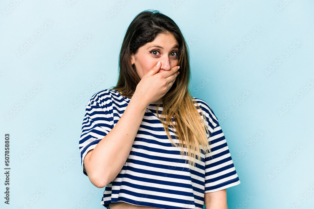 Young caucasian woman isolated on blue background covering mouth with hands looking worried. Young caucasian woman isolated on blue background covering mouth with hands looking worried.