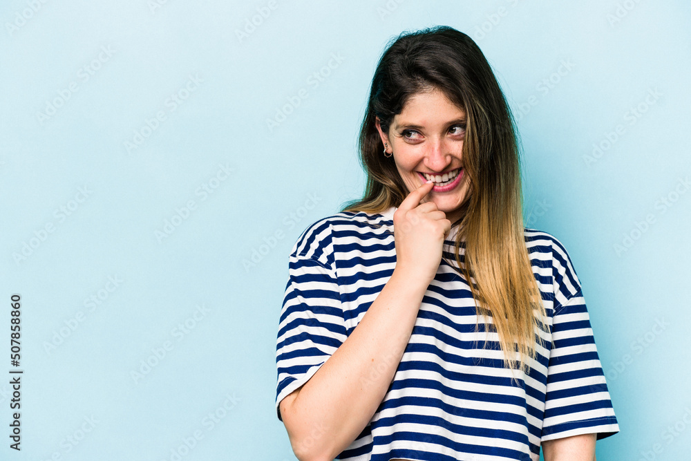 Young caucasian woman isolated on blue background relaxed thinking about something looking at a copy space. Young caucasian woman isolated on blue background relaxed thinking about something looking at a copy space.