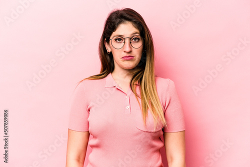 Young caucasian woman isolated on pink background sad, serious face, feeling miserable and displeased.