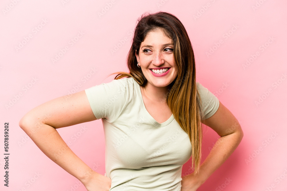 Young caucasian woman isolated on pink background laughs happily and has fun keeping hands on stomach. Young caucasian woman isolated on pink background laughs happily and has fun keeping hands on stomach.