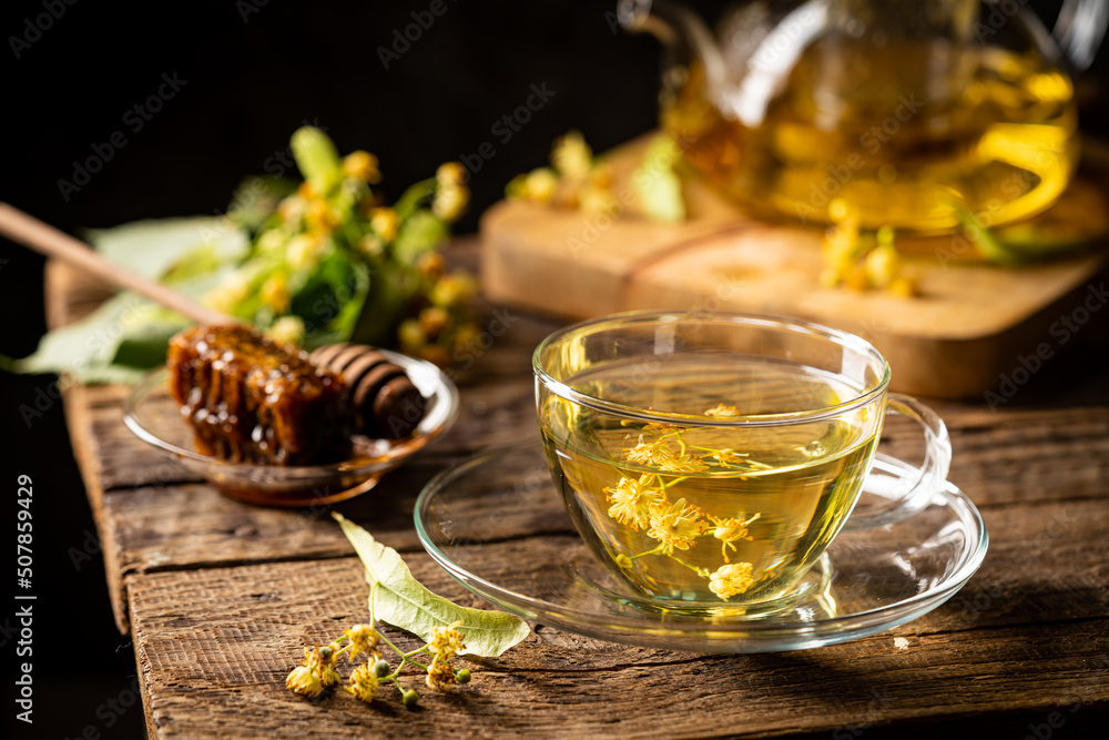 Cup of herbal tea with linden flowers on dark background - obrazy, fototapety, plakaty 