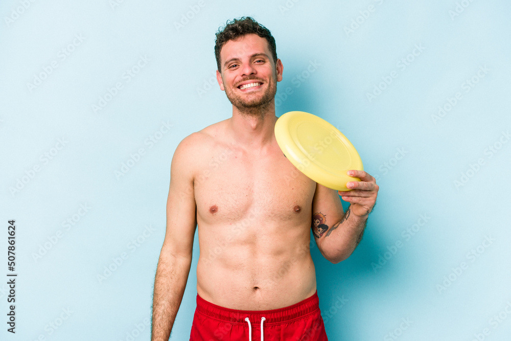 Young caucasian man playing with frisky isolated on blue background happy, smiling and cheerful.