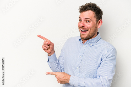 Young caucasian man isolated on white background pointing with forefingers to a copy space, expressing excitement and desire.