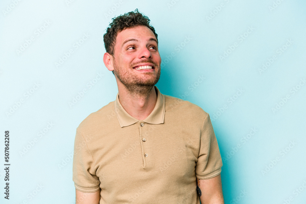Fototapeta premium Young caucasian man isolated on blue background relaxed and happy laughing, neck stretched showing teeth.