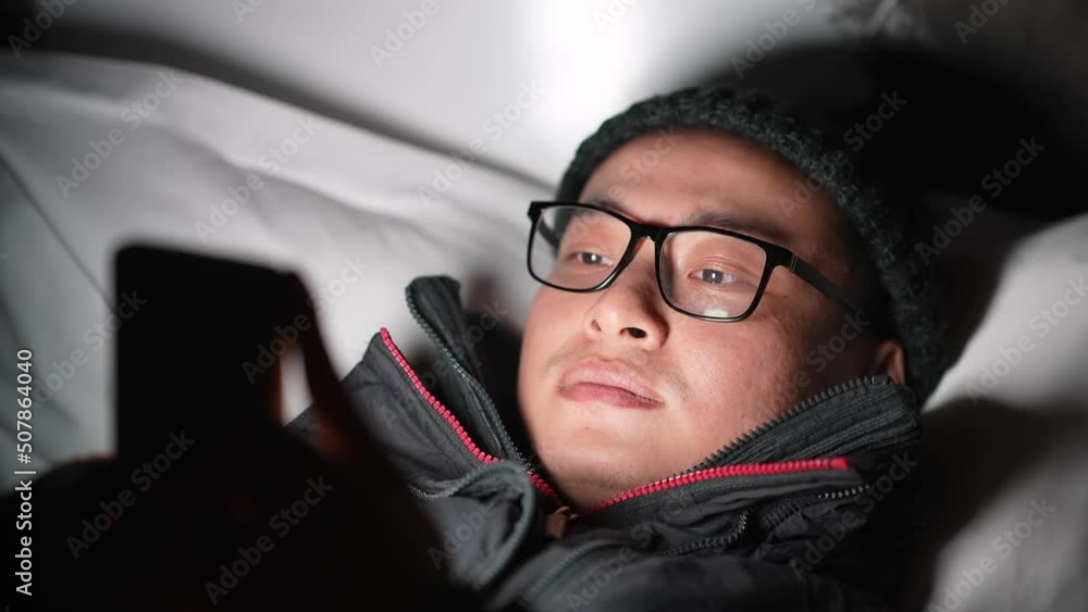 young chinese man lying and playing with mobile phone at night
young chinese man lying and playing with mobile phone at night