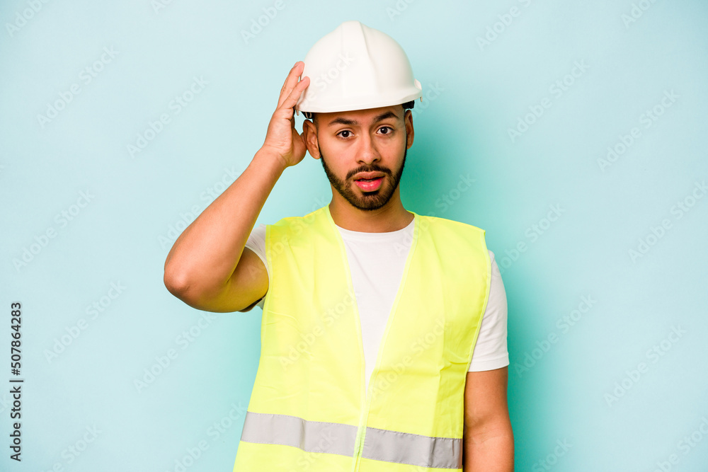Young laborer hispanic man isolated on blue background being shocked, she has remembered important meeting.