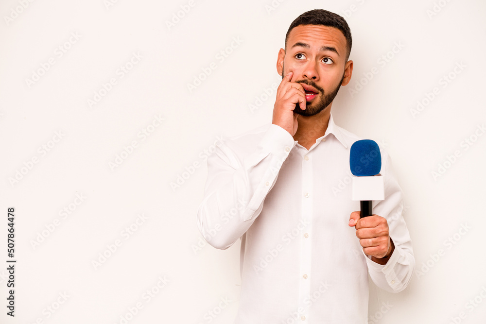 Naklejka premium Young hispanic TV presenter isolated on blue background relaxed thinking about something looking at a copy space.