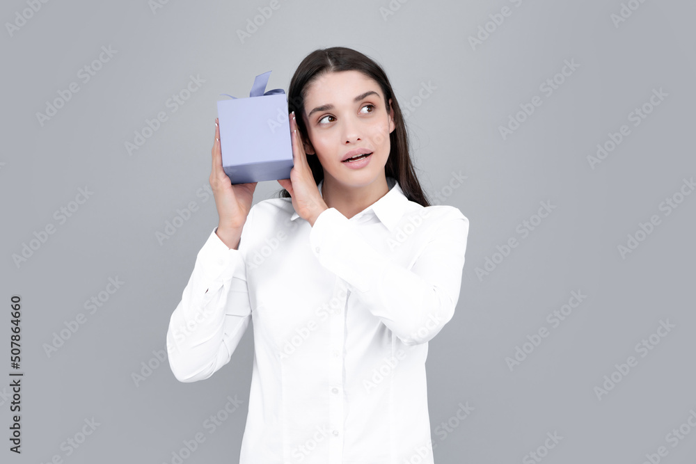 Attractive woman with present box posing with surprised face expression on gray background. Girl holding gift decorated with ribbon. Valentine day, birthday, happy new year gift people concept. Attractive woman with present box posing with surprised face expression on gray background. Girl holding gift decorated with ribbon. Valentine day, birthday, happy new year gift people concept.