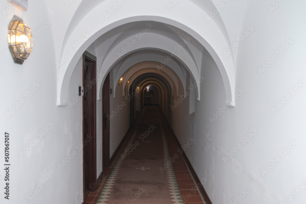 A long, arched hallway. With white walls and ceilings.