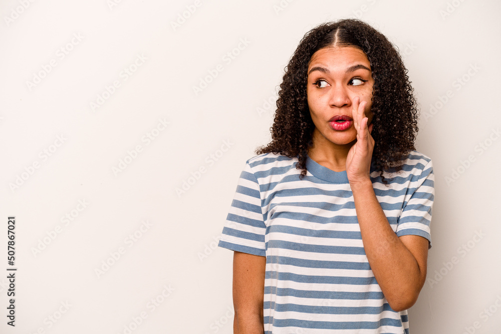 Young African American woman isolated on white background is saying a secret hot braking news and looking aside Young African American woman isolated on white background is saying a secret hot braking news and looking aside