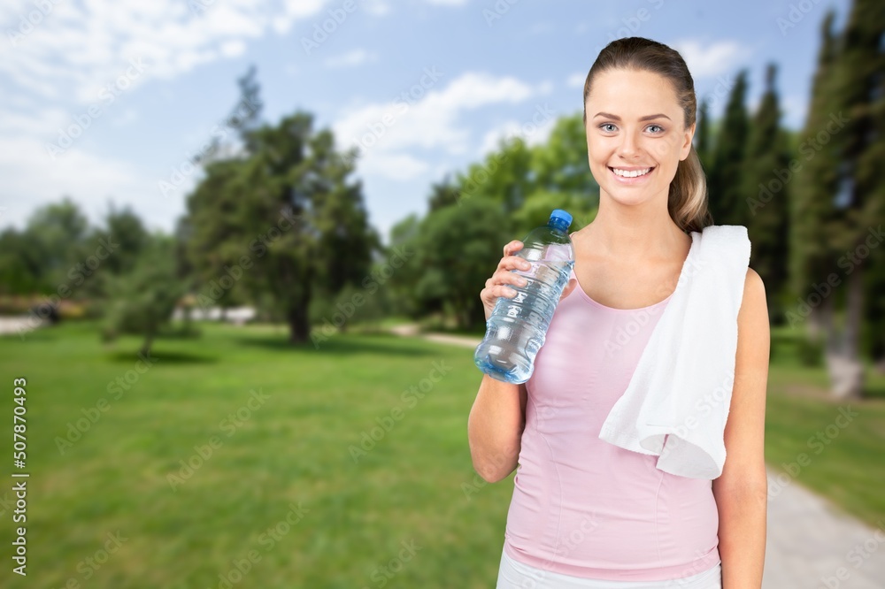 Happy determined athlete, beautiful woman stands on a city and drinks water, resting after early morning jog at sunrise Happy determined athlete, beautiful woman stands on a city and drinks water, resting after early morning jog at sunrise