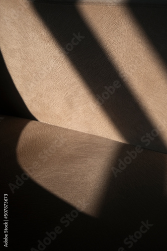 Shadowy abstract fabric detail of an armchair. Vertical beige fabric or textile detail as background.