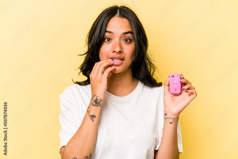 Young hispanic woman holding a keys car isolated on pink background biting fingernails, nervous and very anxious. Young hispanic woman holding a keys car isolated on pink background biting fingernails, nervous and very anxious.
