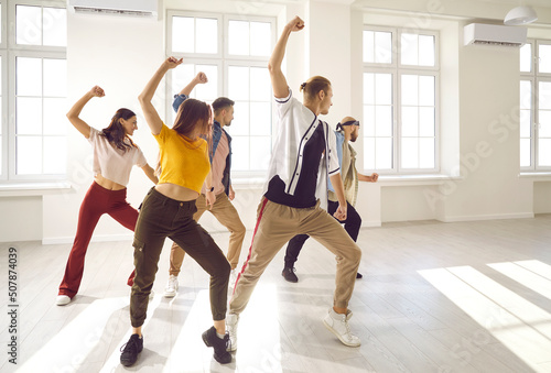 Canvas-taulu Happy active young people in casual street wear dancing together at class or lesson in studio