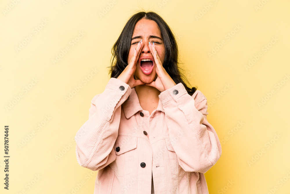 Young hispanic woman isolated on yellow background shouting excited to front.