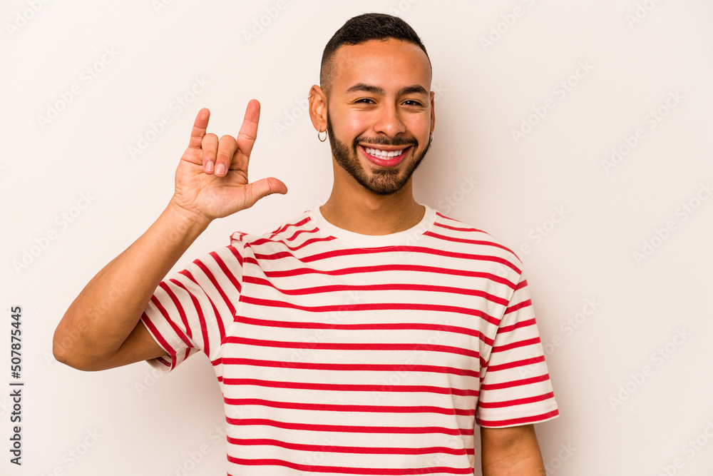 Young hispanic man isolated on white background showing a horns gesture as a revolution concept. Young hispanic man isolated on white background showing a horns gesture as a revolution concept.