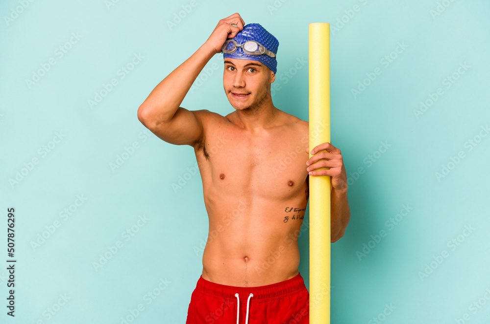 Young caucasian swimmer man holding foam stick isolated on blue background being shocked, she has remembered important meeting.