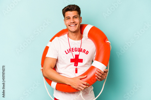 Young caucasian lifeguard isolated on blue background happy, smiling and cheerful.