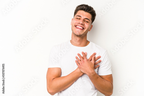 Young caucasian man isolated on white background has friendly expression, pressing palm to chest. Love concept. © Asier