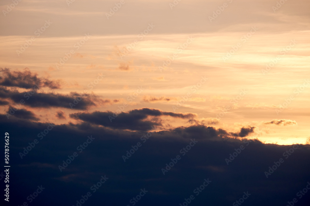 Dark clouds in the evening sunset sky with the setting sun. Dramatic sky during orange sunset