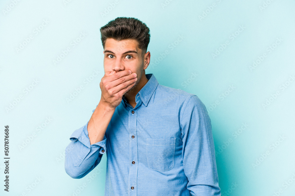 Young caucasian man isolated on blue background covering mouth with hands looking worried. Young caucasian man isolated on blue background covering mouth with hands looking worried.