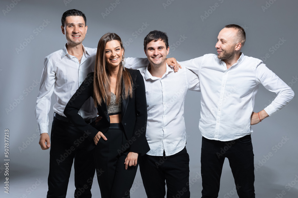 A group of four people, musicians in the studio. Black and white clothing. Enchanting vocalist in stage outfits. Colorful background A group of four people, musicians in the studio. Black and white clothing. Enchanting vocalist in stage outfits. Colorful background