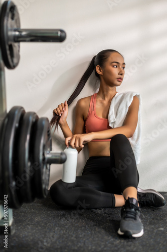 Woman sport girl sitting resting after work out at fitness with fore ground of exercise machine