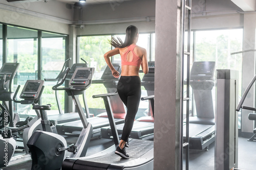 Back scene of woman working out in gym running on running machine