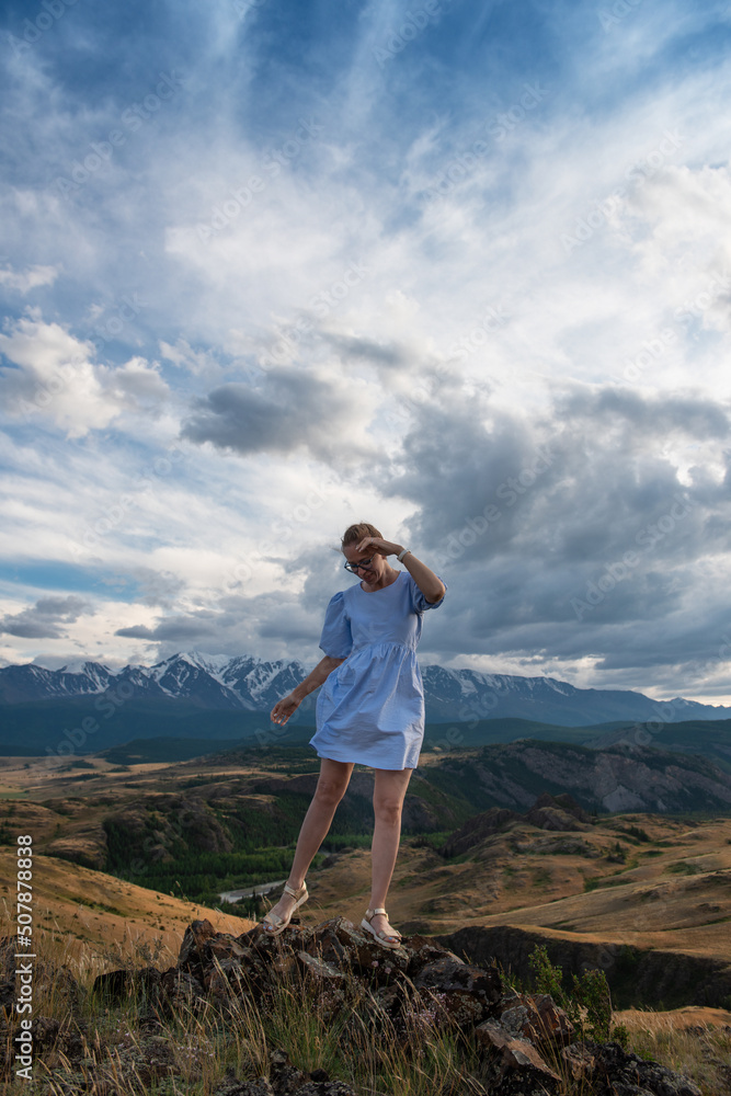 Woman in blue dress in summer Altai mountains in Kurai steppe