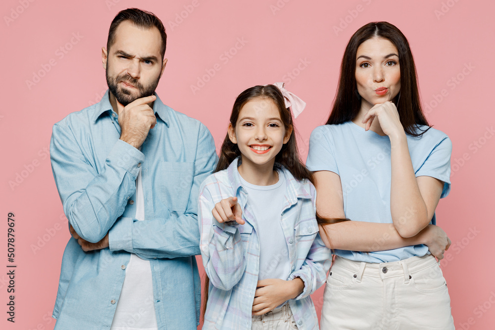 Young minded parent mom dad with child kid daughter teen girl in blue clothes look camera point index finger camera on you isolated on plain pastel light pink background Family day parenthood concept Young minded parent mom dad with child kid daughter teen girl in blue clothes look camera point index finger camera on you isolated on plain pastel light pink background Family day parenthood concept