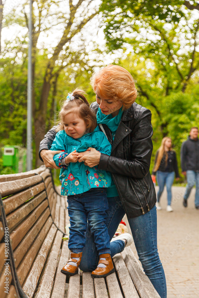 beautiful girl (mother) with a girl (daughter) in the park in the park are sitting on a bench beautiful girl (mother) with a girl (daughter) in the park in the park are sitting on a bench