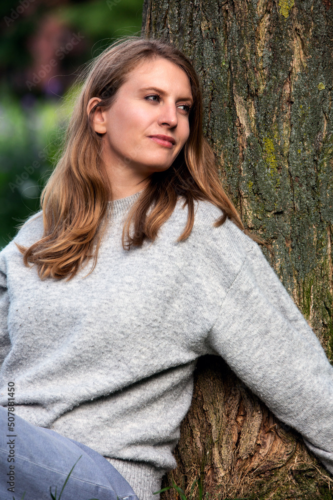 Obraz premium portrait of a blond woman sitting outdoors at a tree