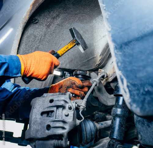 Close up hands of car mechanic adjusting tension in vehicle suspension element. Ball joint replacement. Professional auto service.
