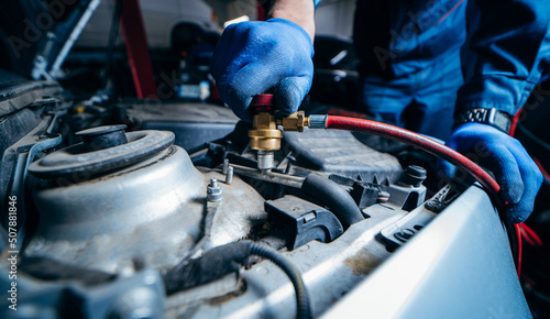 Photography Close up hands of car mechanic connects air conditioning system in auto service