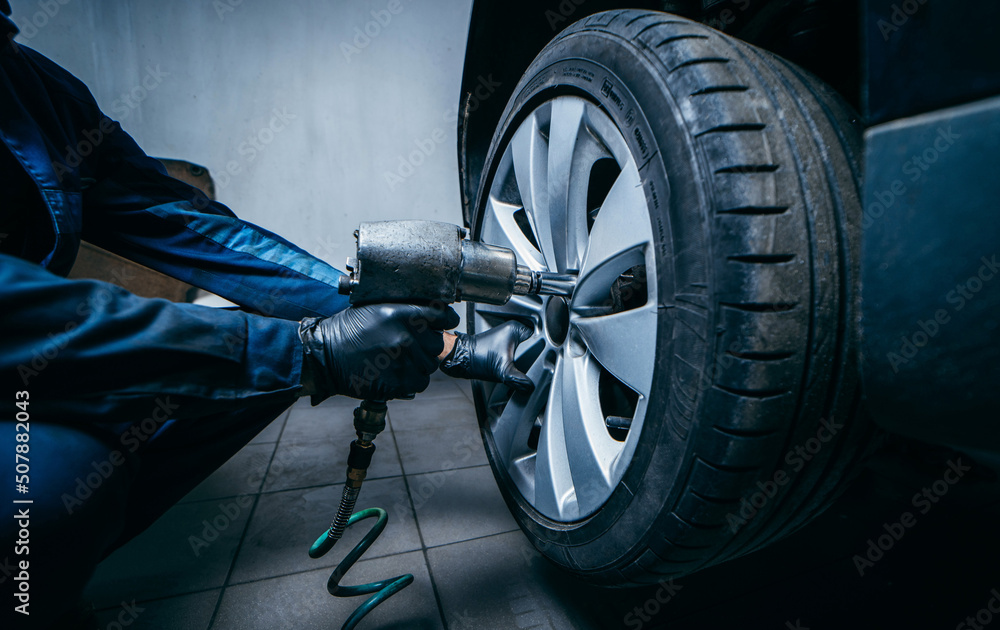 Hands of professional car mechanic changing car wheel in auto repair service. Close up Hands of professional car mechanic changing car wheel in auto repair service. Close up