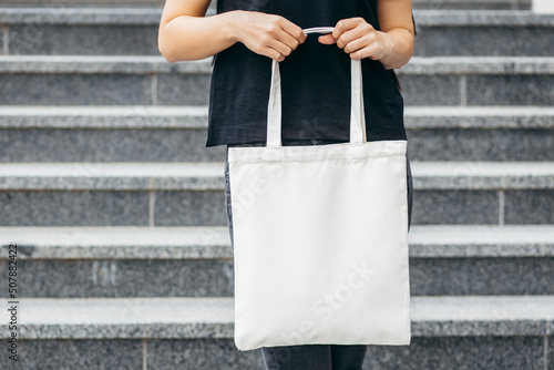 Young model girl on the street holding white eco bag, mock up
