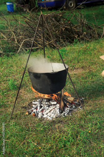 Cauldron suspended over the fire, cooking in the field. Food is cooked in the open air on the fire