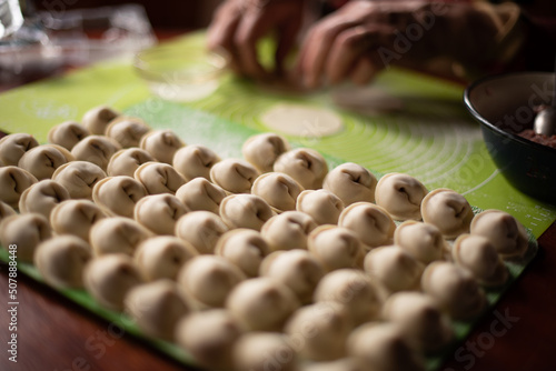 senior woman making dumplings in the kitchen hands close up