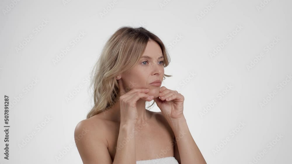 Face lifting massage. Semi profile portrait of middle aged lady massaging chin against skin sagging, empty space Face lifting massage. Semi profile portrait of middle aged lady massaging chin against skin sagging, empty space