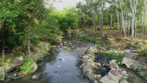 a stream of polluted water and trash in the woods photo