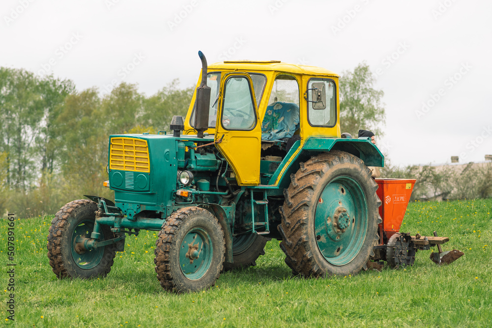 Old farm tractor Belarus on the green grass in an agricultural field in spring ready for the plowing and sowing Old farm tractor Belarus on the green grass in an agricultural field in spring ready for the plowing and sowing