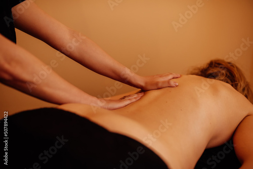 Unrecognizable masseuse performing a back massage to a woman in a beauty and wellness center