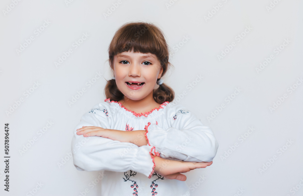 Beautiful little Ukrainian girl happily smiling. First-grade student with fall out baby teeth. Beautiful little Ukrainian girl happily smiling. First-grade student with fall out baby teeth.