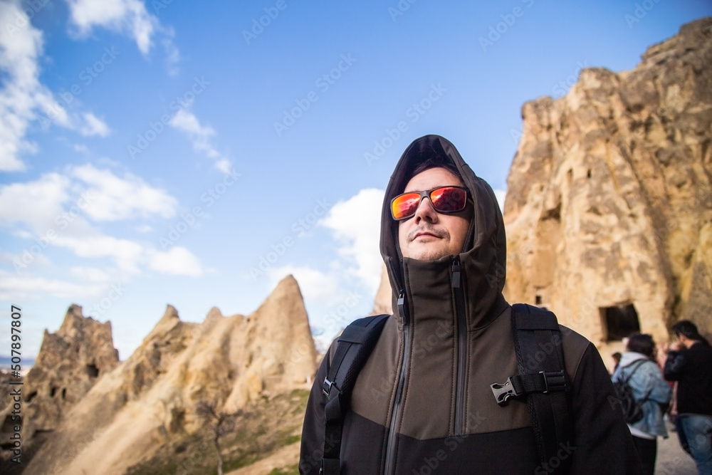 Smiling young man traveler enjoying a vacation in mountains and valleys of Cappadocia Turkey. Healthy lifestyle tourist man active vacation hiking outdoor portrait. Smiling young man traveler enjoying a vacation in mountains and valleys of Cappadocia Turkey. Healthy lifestyle tourist man active vacation hiking outdoor portrait.