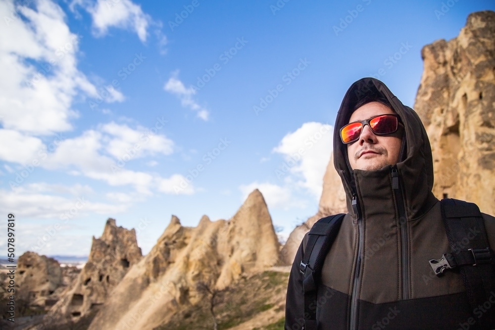 Smiling young man traveler enjoying a vacation in mountains and valleys of Cappadocia Turkey. Healthy lifestyle tourist man active vacation hiking outdoor portrait. 