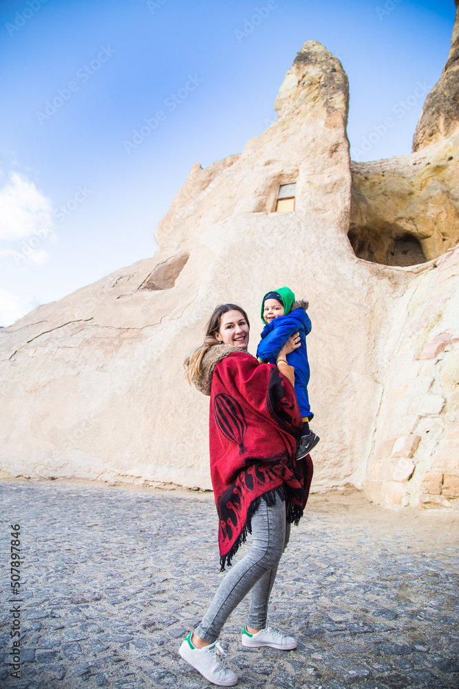 Mother and baby boy traveling enjoying a vacation in desert Cappadocia Turkey. Mom and tourist kid in blue clothing outdoor portrait. Happy woman and child active vacation hiking