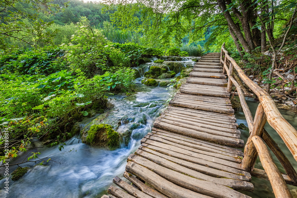 Obraz premium Plitvice, Croatia - Wooden walkway in Plitvice Lakes National Park on a bright summer day with crystal clear turquoise water, small waterfalls and green summer foliage