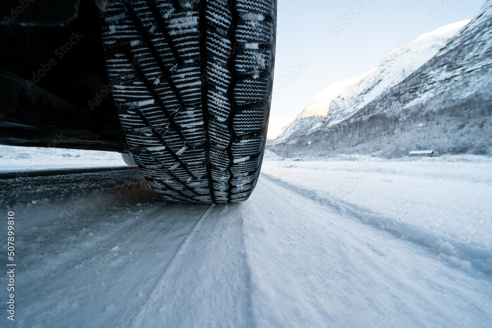 View from the bottom of the car on a snowy road where you can see the tread of a winter tire in the snow