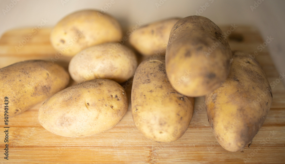 peeled potatoes lie on the surface of a wooden table in the kitchen. Potato supply problems, sales restrictions, global famine, potato shortage peeled potatoes lie on the surface of a wooden table in the kitchen. Potato supply problems, sales restrictions, global famine, potato shortage
