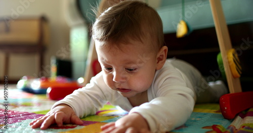 Baby infant lying on floor touching play mat, toddler discovering exploring the world
